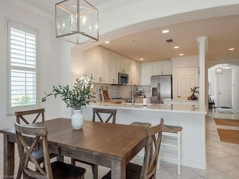 Tiled dining space with crown molding, plenty of natural light, and an inviting chandelier