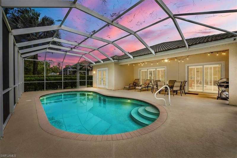 Pool at dusk featuring a lanai, ceiling fan, and a patio