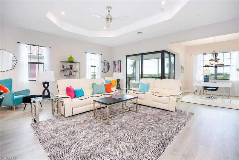 Living room with baseboards, wood finished floors, recessed lighting, a raised ceiling, and ceiling fan with notable chandelier