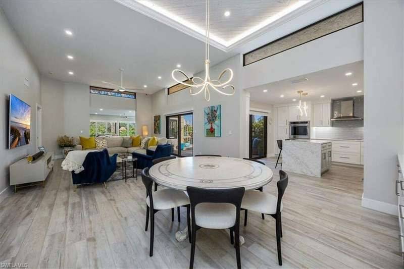 Dining area featuring a notable chandelier, a towering ceiling, plenty of natural light, and light wood-type flooring