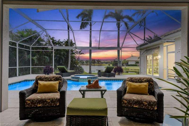 Pool at dusk with an in ground hot tub, a patio, a water view, and glass enclosure