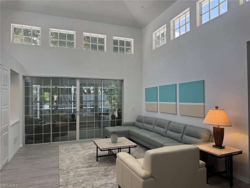 Living room featuring healthy amount of natural light, high vaulted ceiling, and wood finished floors