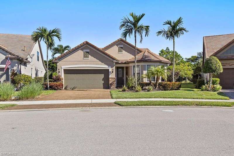View of front of home featuring stucco siding, driveway, a front yard, a garage, and a tiled roof