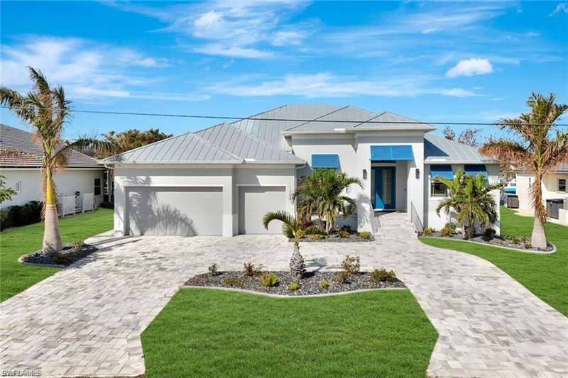 View of front facade featuring a standing seam roof, a metal roof, decorative driveway, an attached garage, and a front yard