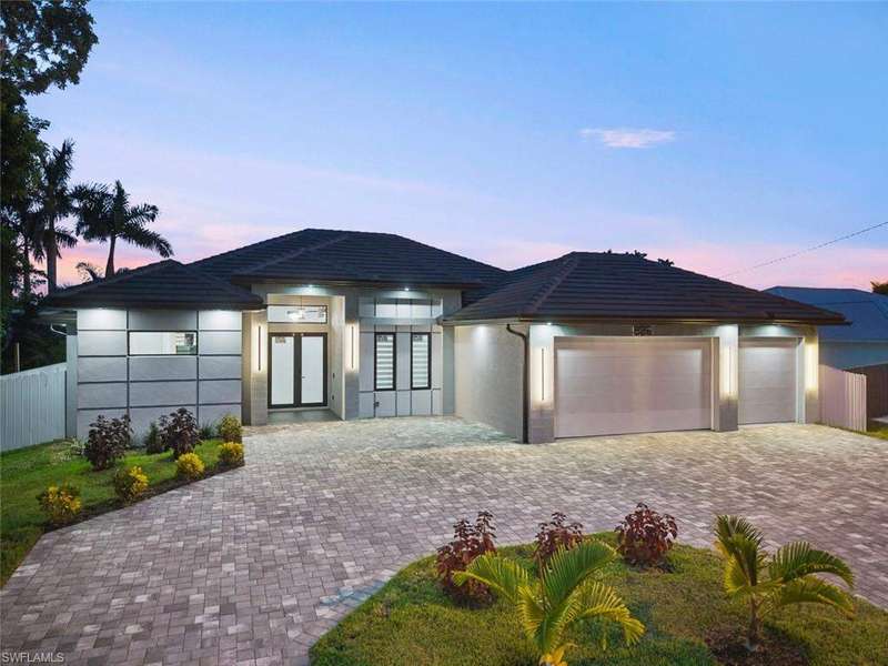 View of front facade featuring a garage, decorative driveway, stucco siding, and a tile roof