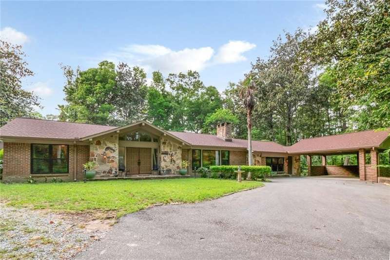 Ranch-style house featuring a chimney, aphalt driveway, stone siding, a front yard, and brick siding