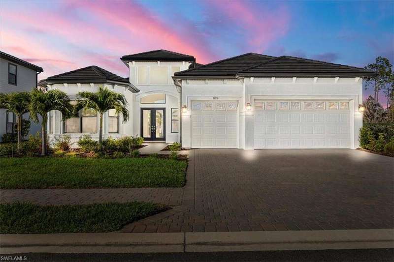 View of front facade featuring decorative driveway, an attached garage, french doors, and stucco siding