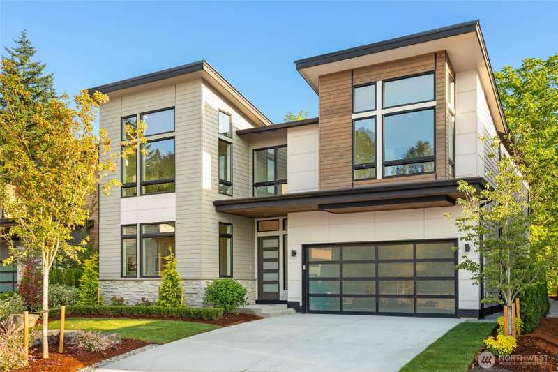 Stunning NW Contemporary exterior features Clear line cedar siding with stone veneer. Custom landscape design with full yard irrigation, spacious driveway with contemporary glass panel garage