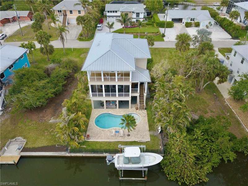 Rear view of home with 2 decks overlooking the salt water pool, boat lift and canal with direct access to Estero Bay and the Gulf of America.