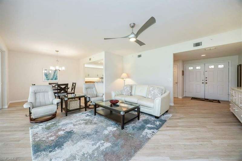 Living room with ceiling fan with notable chandelier and light hardwood / wood-style floors