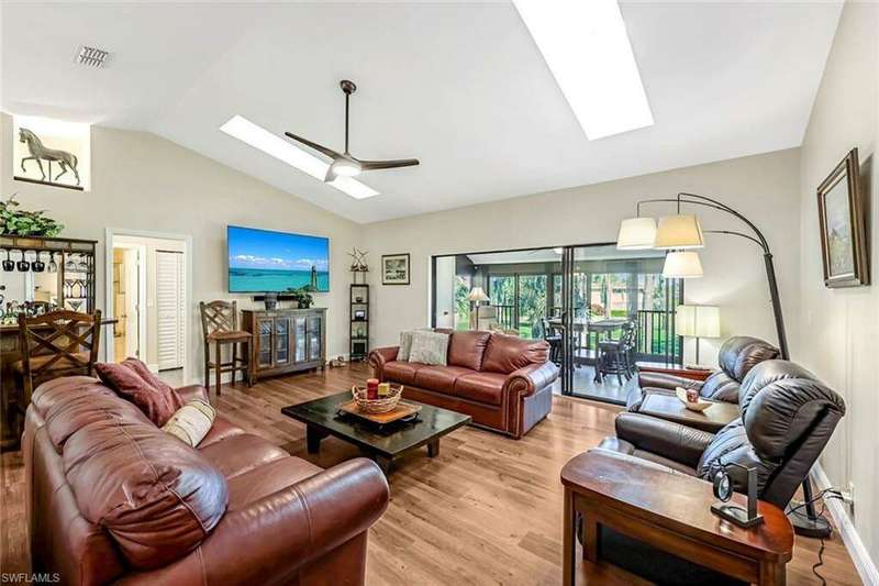 Living room with light wood-type flooring, lofted ceiling with skylight, and ceiling fan