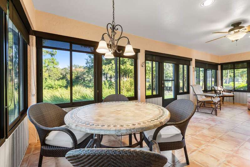 Kitchen featuring ceiling fan, dark stone countertops, stainless steel dishwasher, light tile patterned floors, and brown cabinetry
