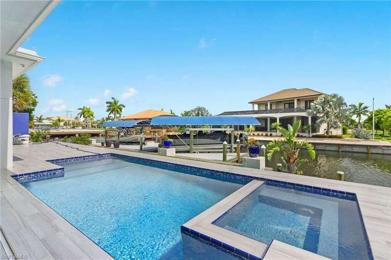 View of pool featuring a patio, a boat dock, an in ground hot tub, and a water view